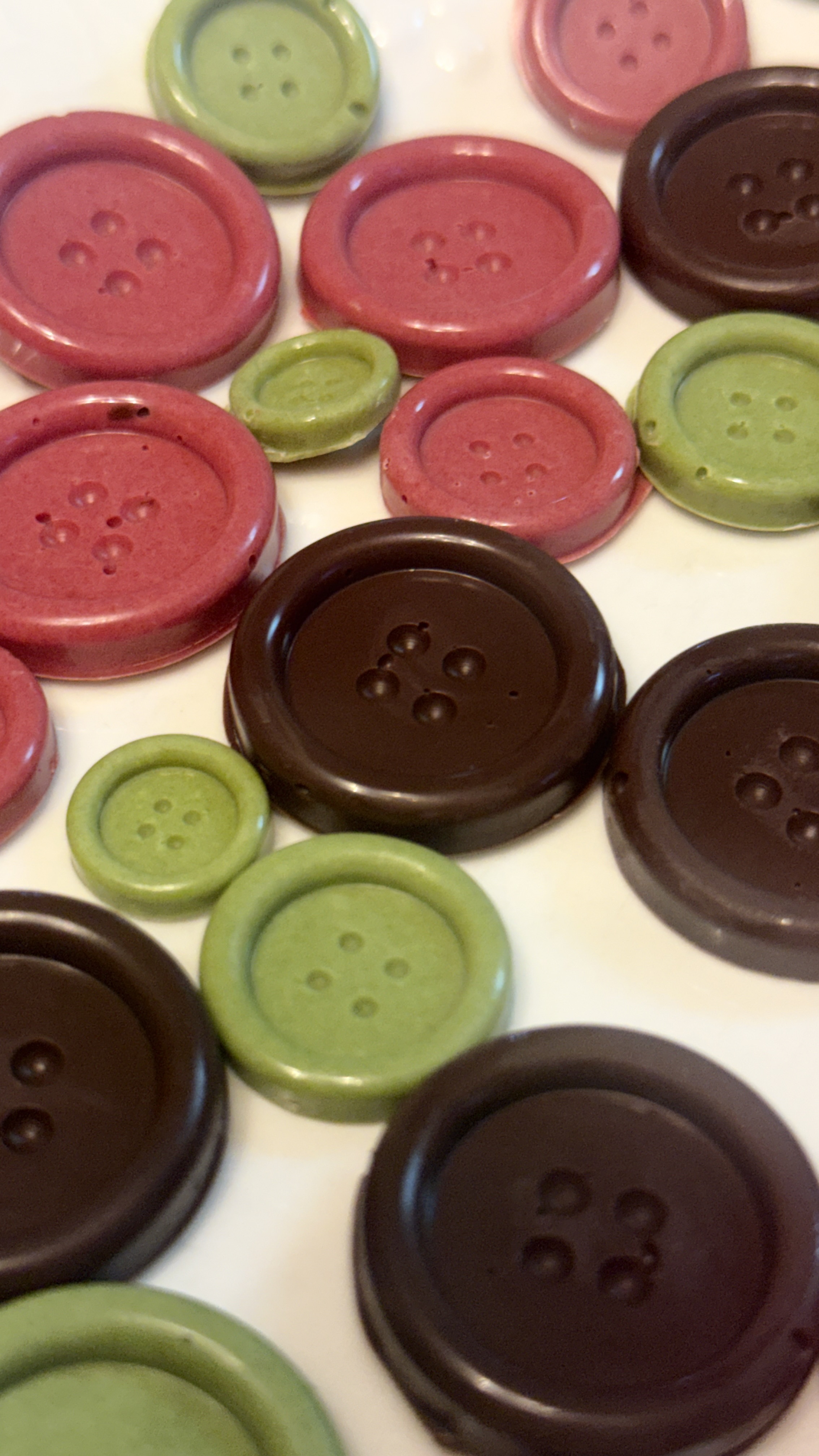 Chocolate buttons in cocoa brown, rosy red, and leafy green.