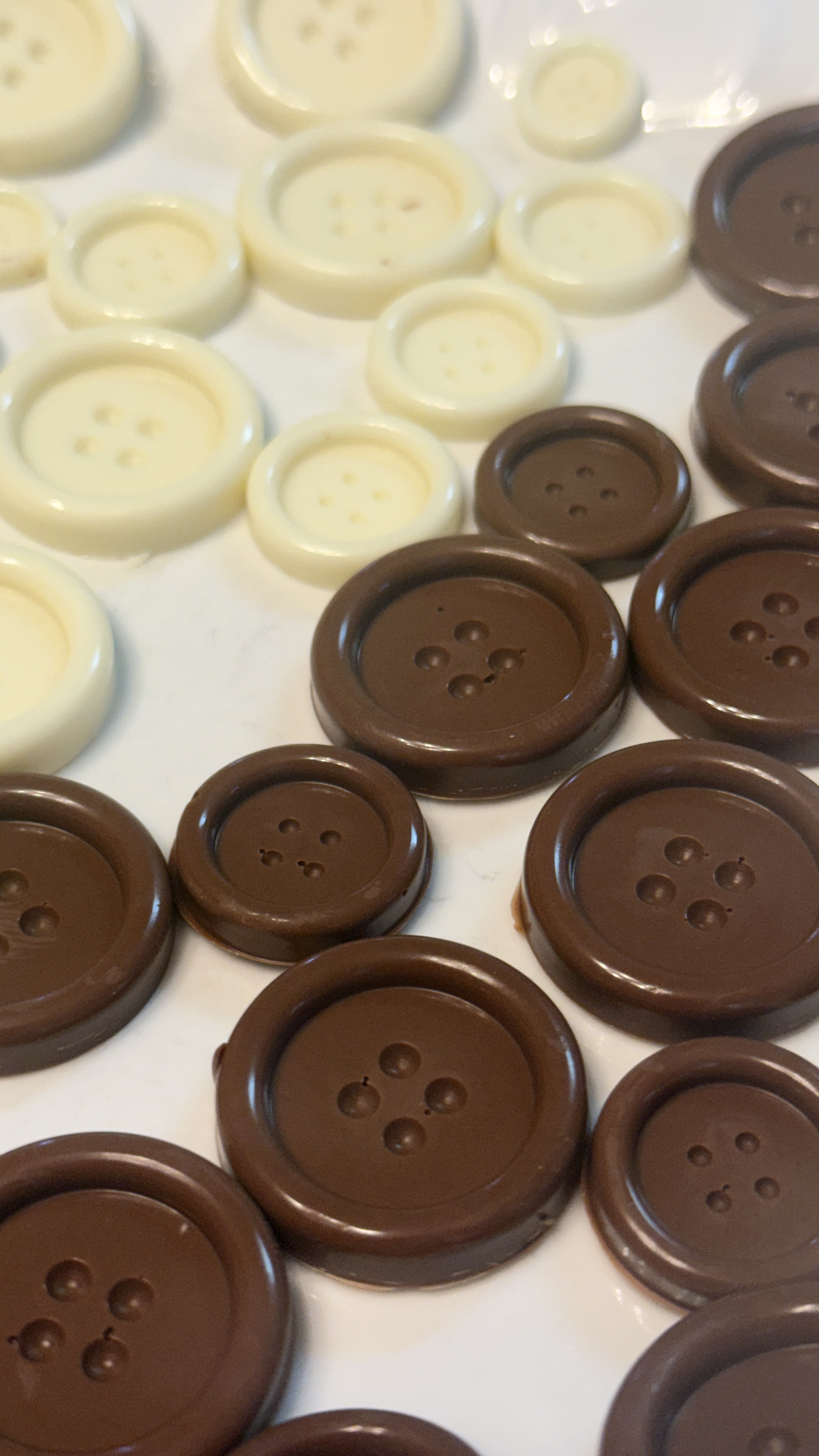 Cream and cocoa-colored chocolate buttons arranged together.