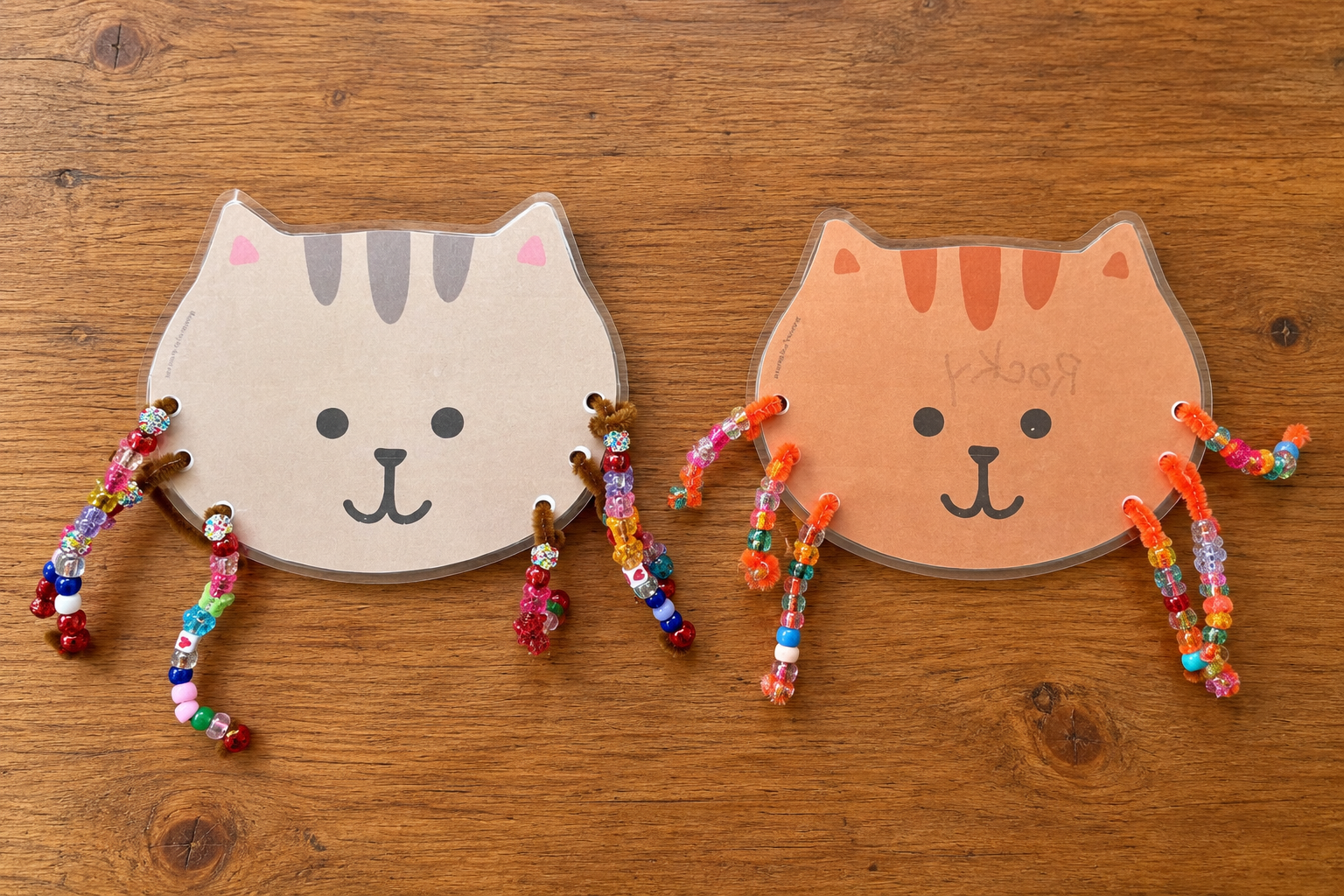 Our gray and orange kitten crafts with colorful beaded whiskers on a wooden table